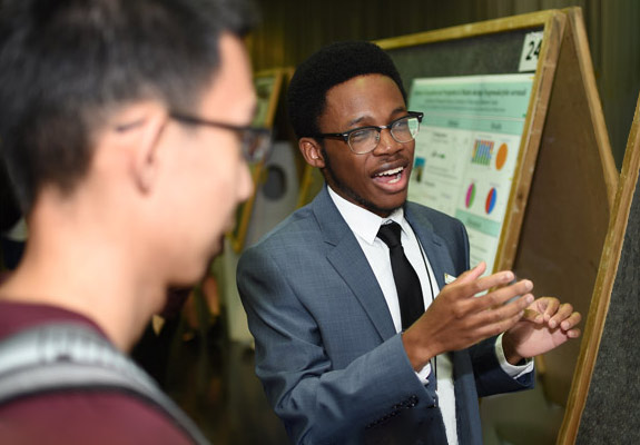 student presenting research displayed on poster