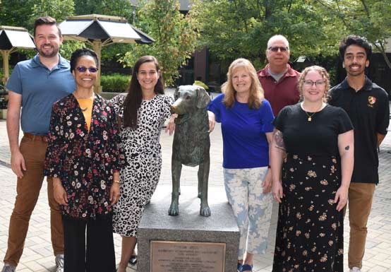 group photo of the AETP staff standing around the statue of true grit
