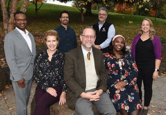 The staff of INDS standing casually outside in front of the Fine Arts building