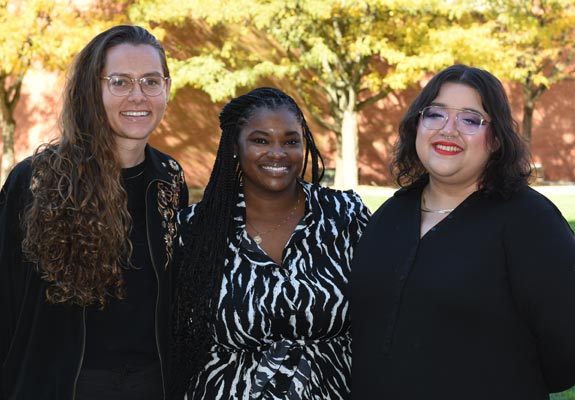 The director of the women's center flanked by two of her associates standing outside enjoying the fall weather on campus.