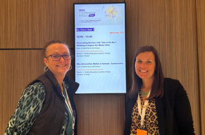 Two professionals standing infront of a conference sign